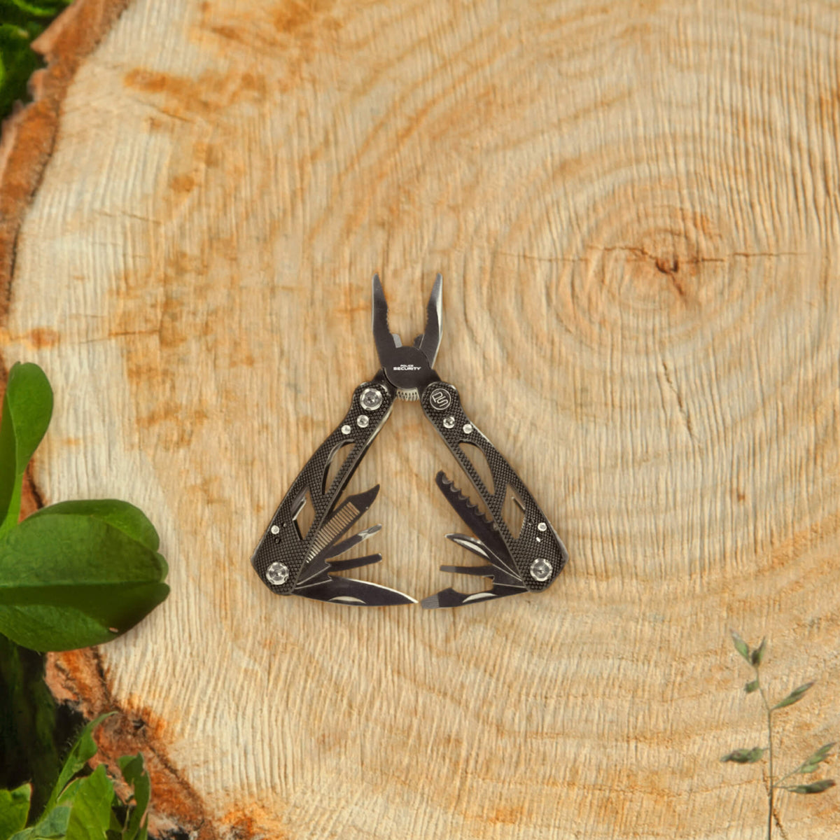 A black multi-tool with pliers on a stump with clovers next to it