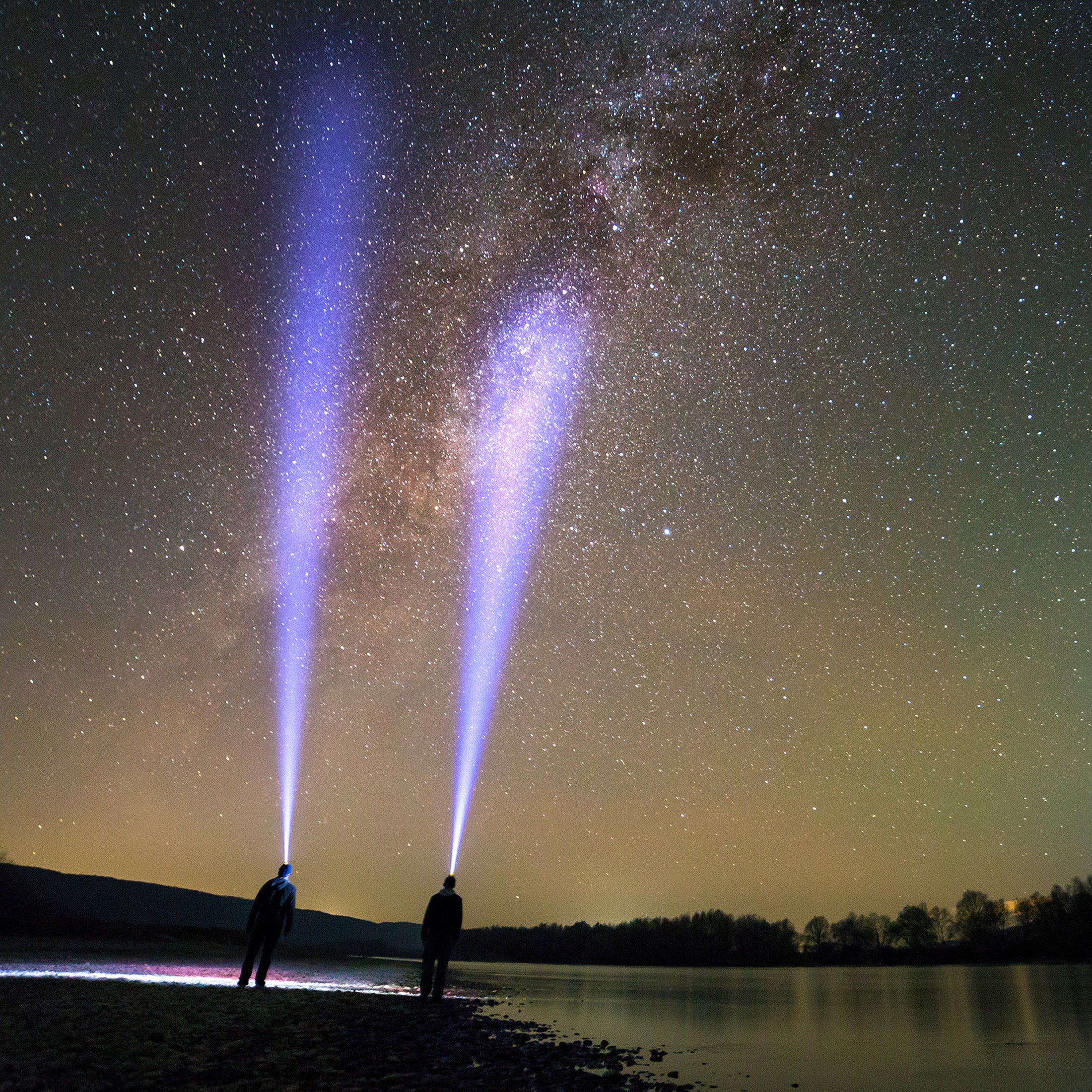 The Police Security Long Throw Twin Power flashlight shining up into the sky on a beach