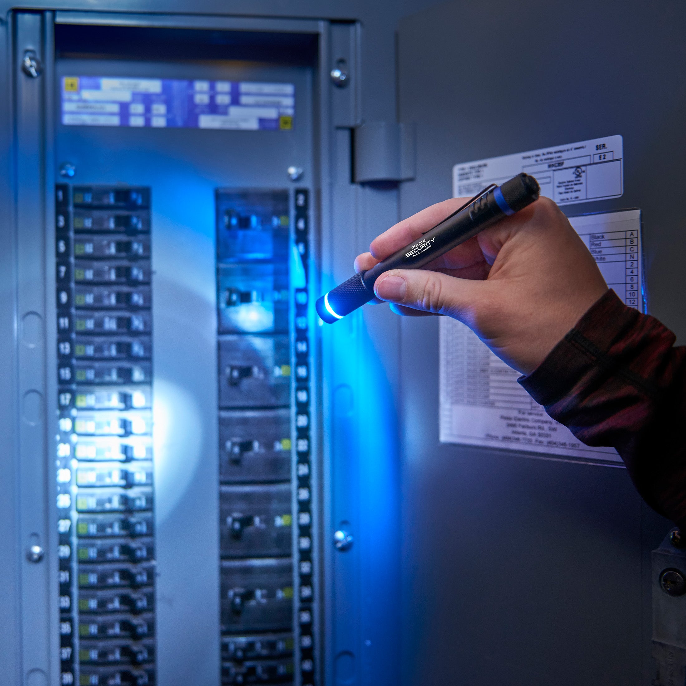 an image of a hand holding the Black AURA penlight lighting a fuse box