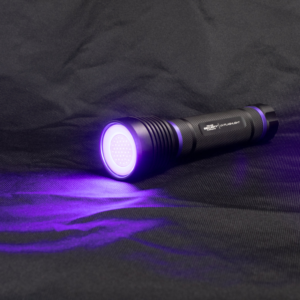 The Police Security UV flashlight turned on while sitting on a mesh tarp