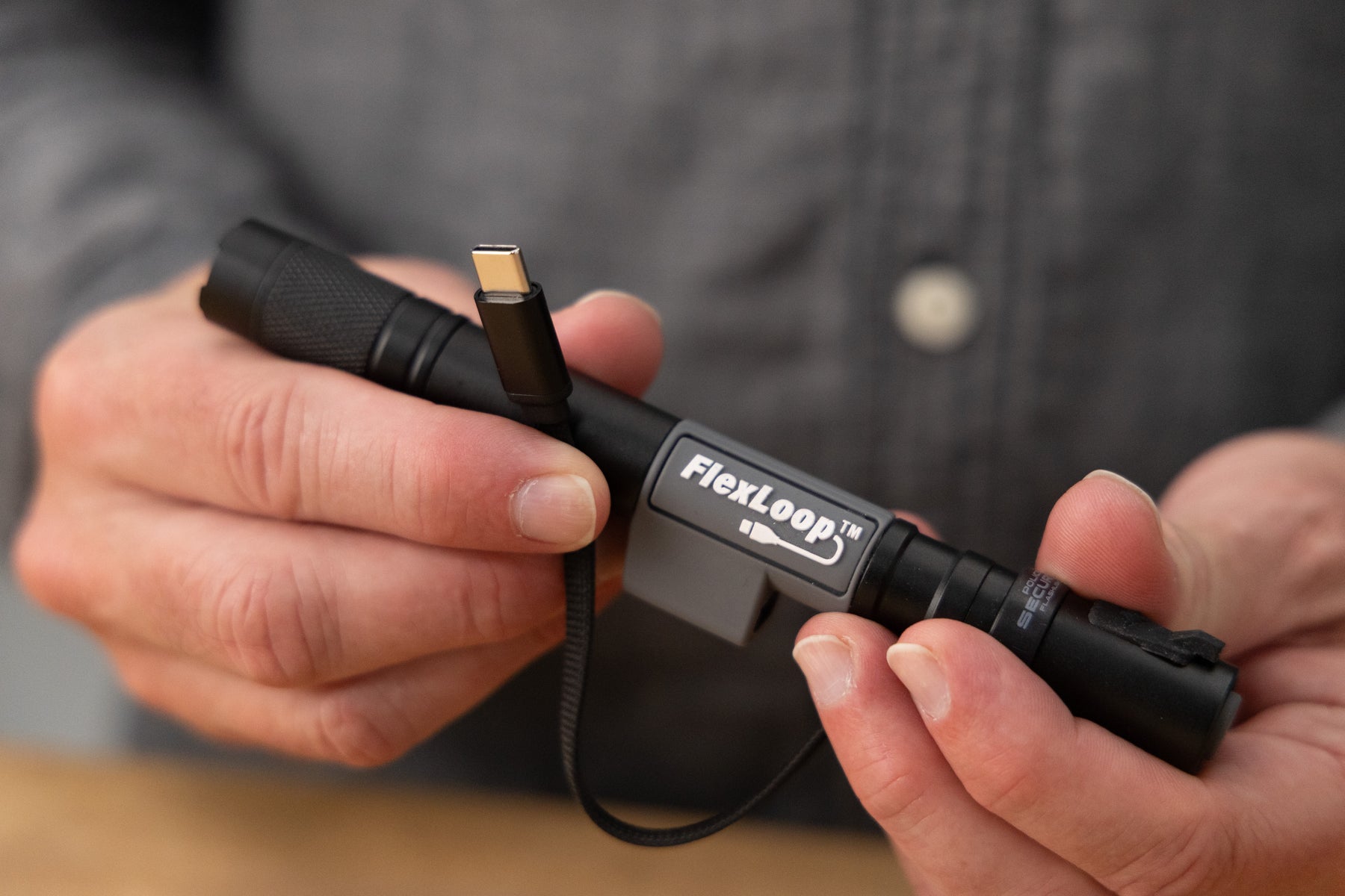 Person holding a FlexLoop Aura R flashlight with a close-up of the product.