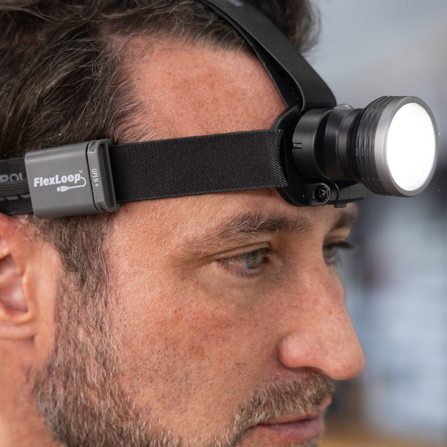 Person wearing a headlamp with 'FlexLoop' branding on a blurred background