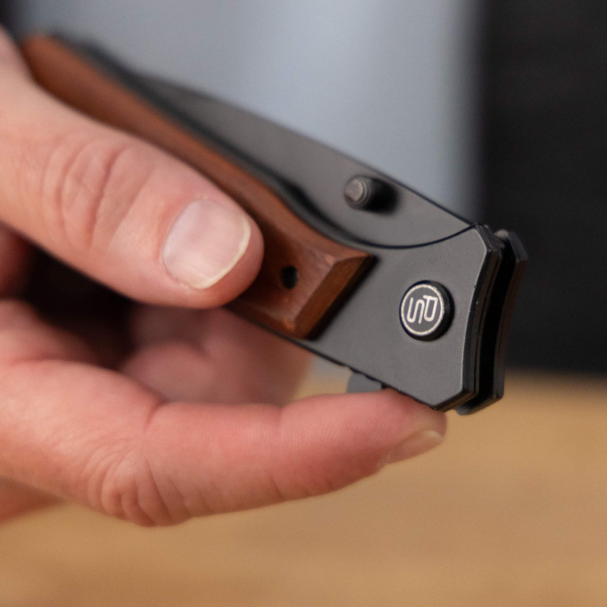A man holding the Ridgeline pocket knife with a finger on the flipper opener
