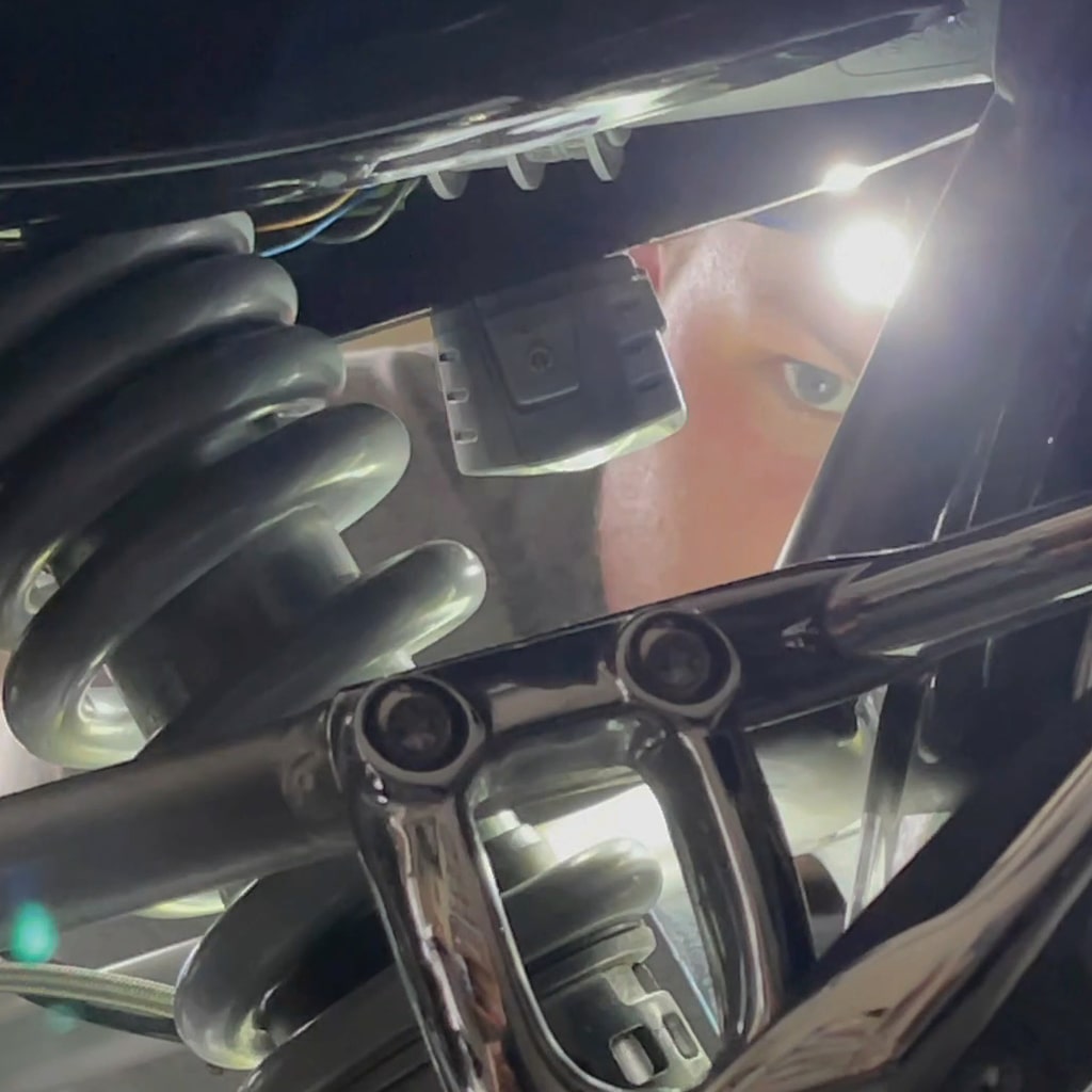 a man looking into the motorcycle with a headlamp on his head