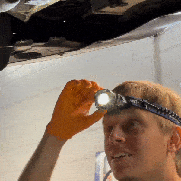 An gif of a blonde mechanic turning his headlamp on and off