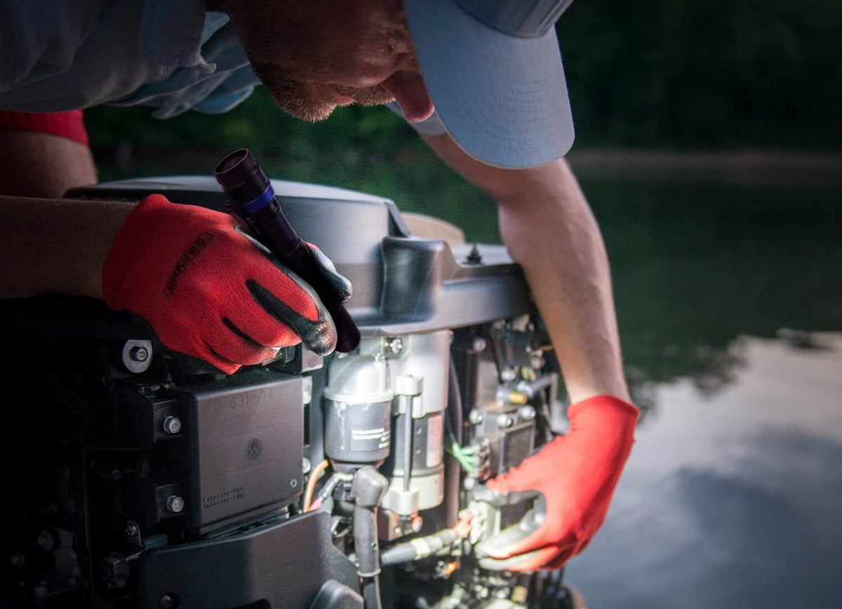 A man using a flashlight to inspect a boat engine