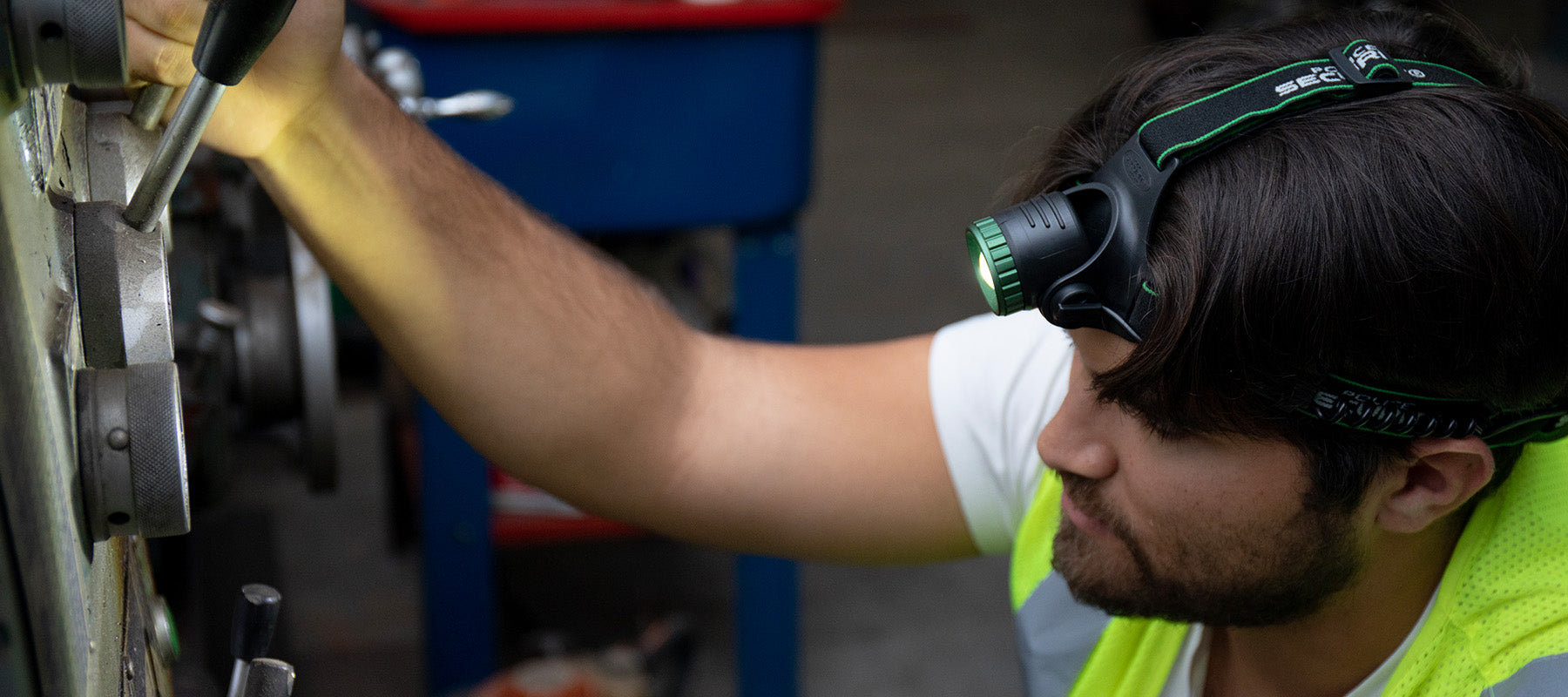 man wearing bright headlamp working on motorcycle
