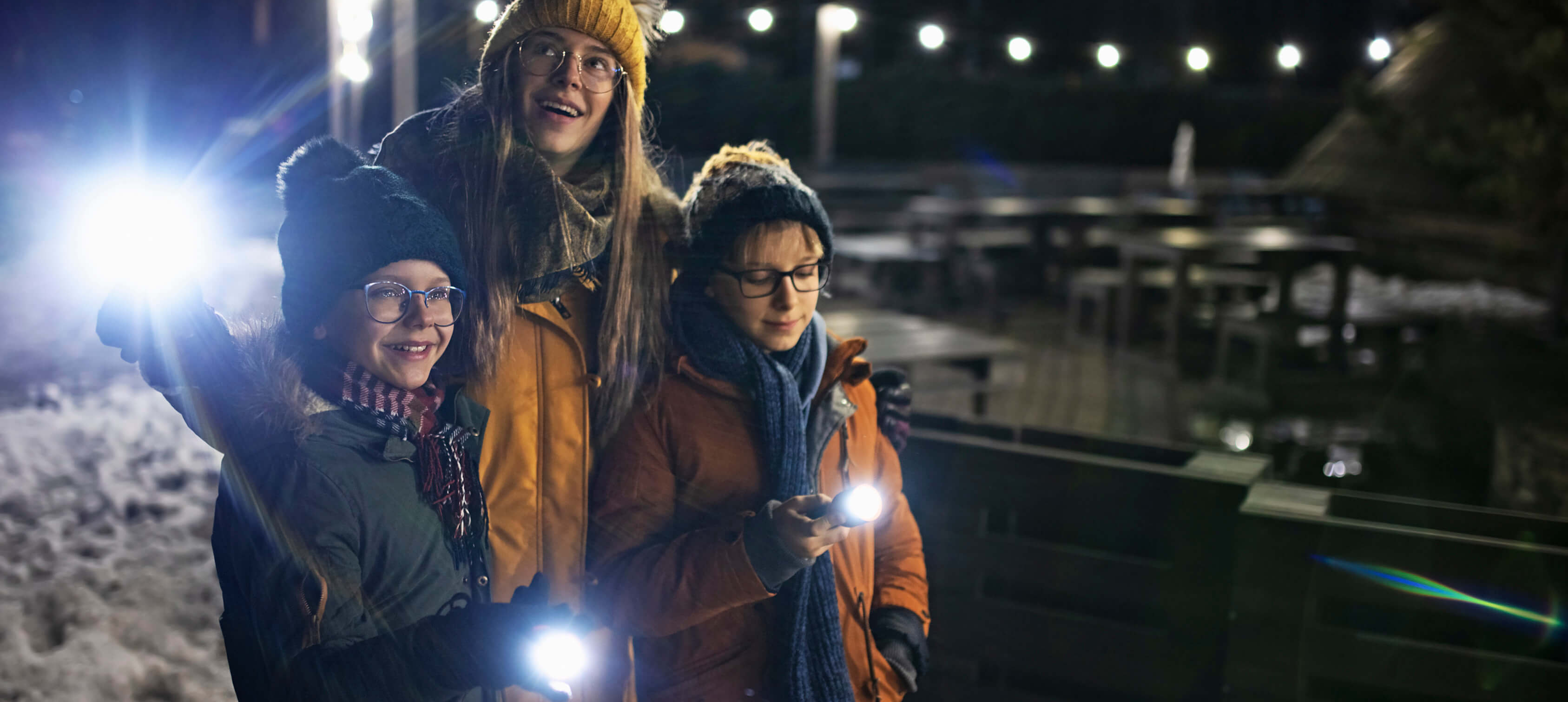A mother and her two kids walking on the beach at night