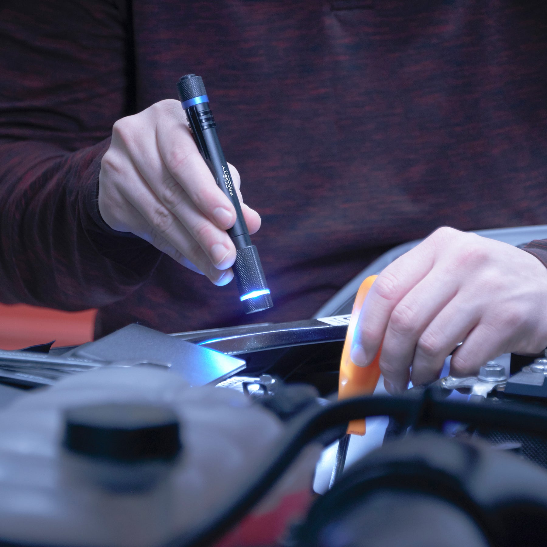 an image of two hands fixing the engine with the left hand screwing something and the right holding the AURA PENLIGHT