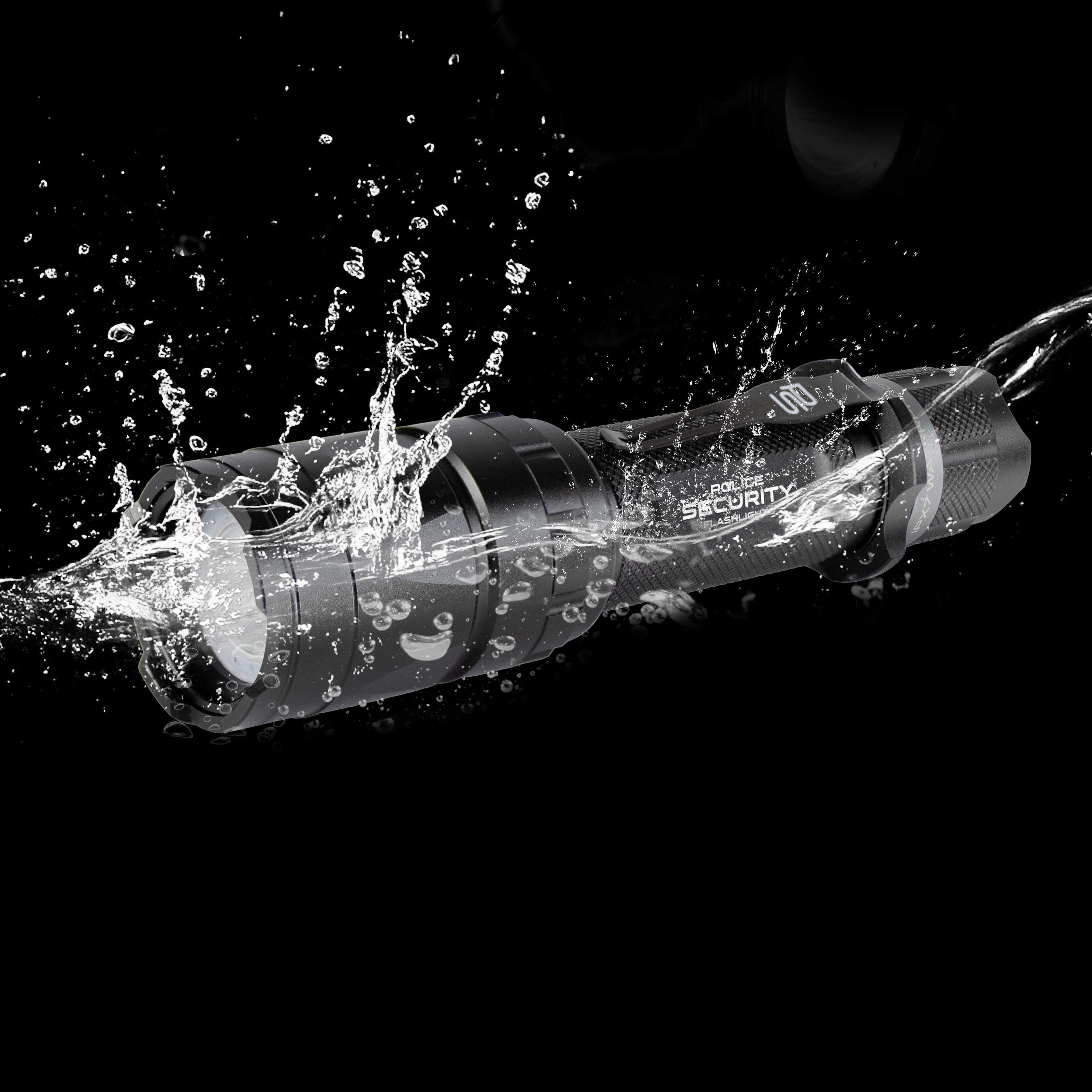 A black Trac Tact-R tactical flashlight, shown diagonally amidst a dramatic splash of water against a solid black background.