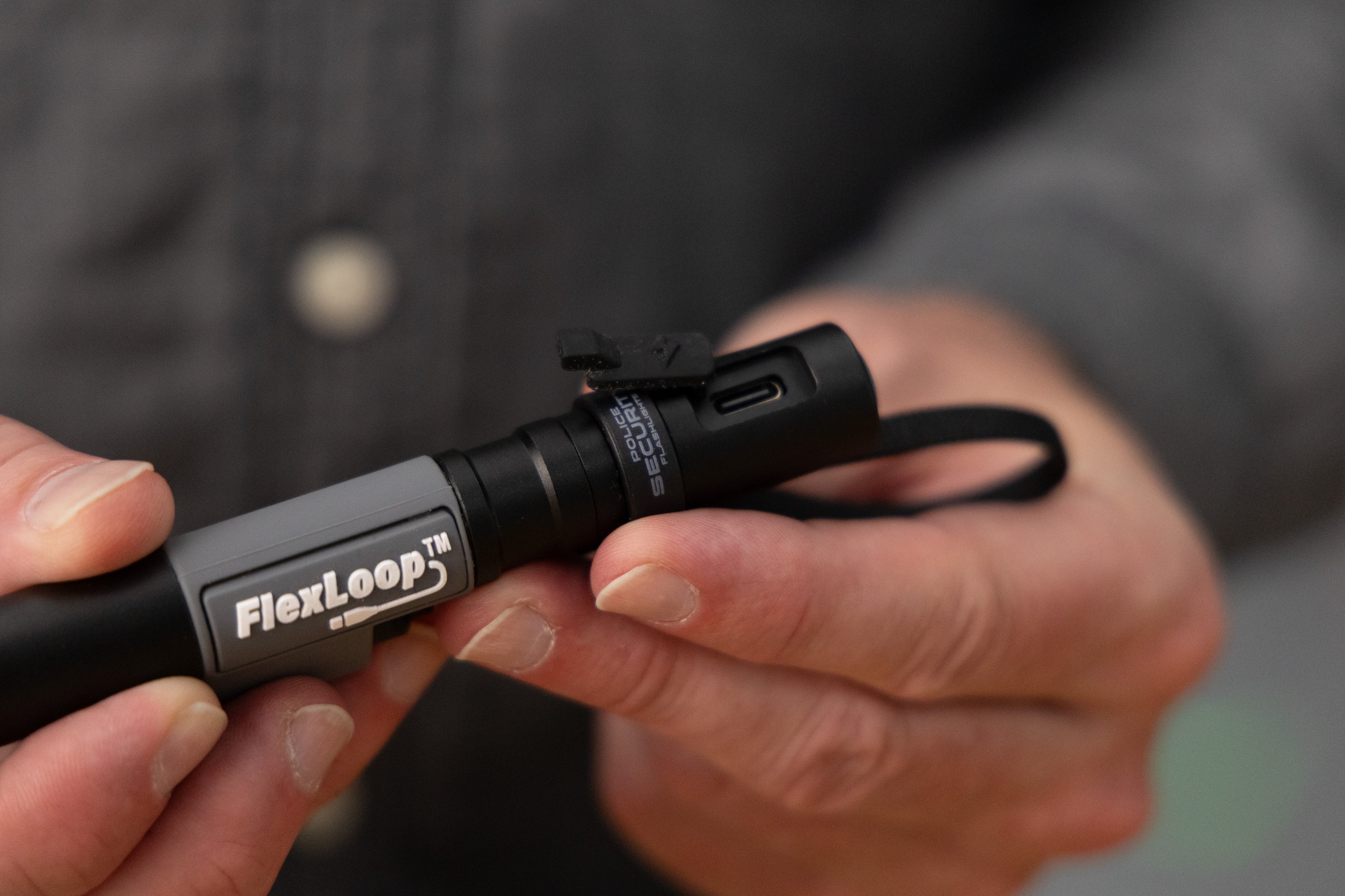 Person holding a black Flexloop Aura R flashlight with 'FlexLoop' branding.