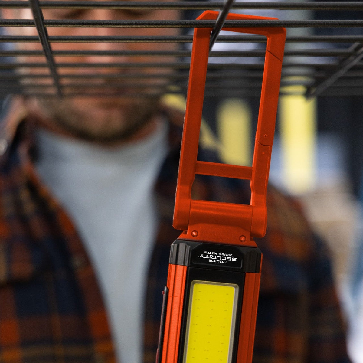 The Kickstand R Mini work light in orange hanging from a wire rack from its carabiner hook