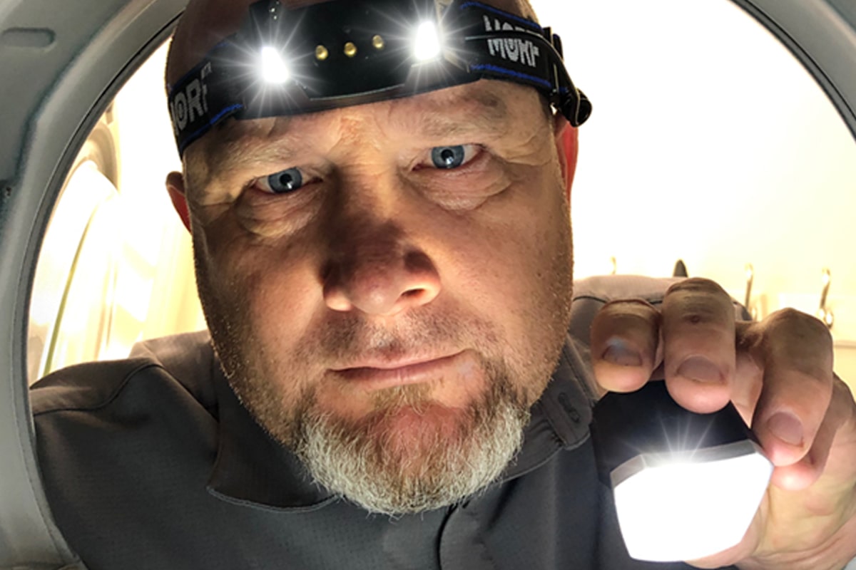 a closeup of a man wearing a MORF headlamp & holding it's main light in his hand