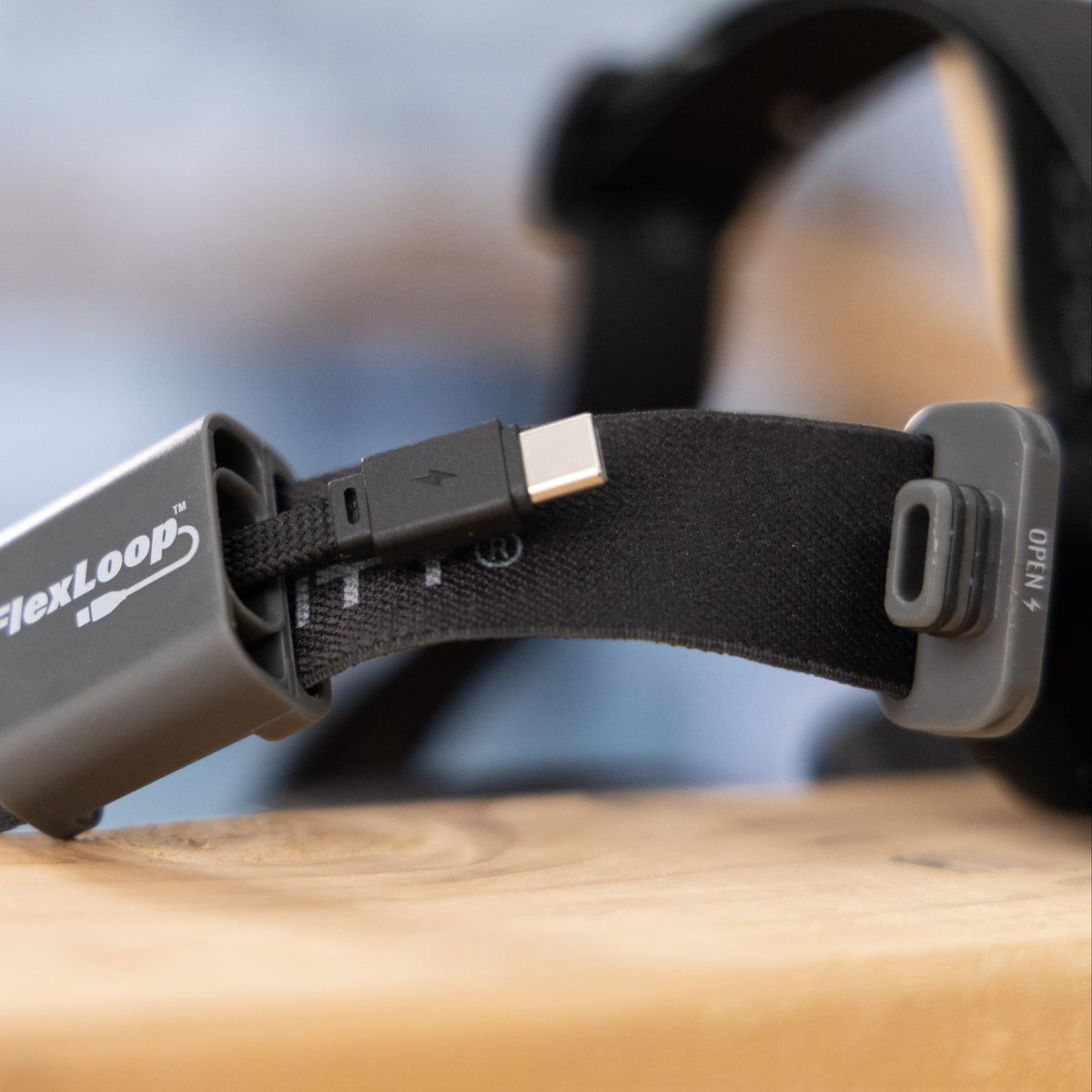 FlexLoop headlamp with integrated charging cord exposed on a wooden surface with a blurred background