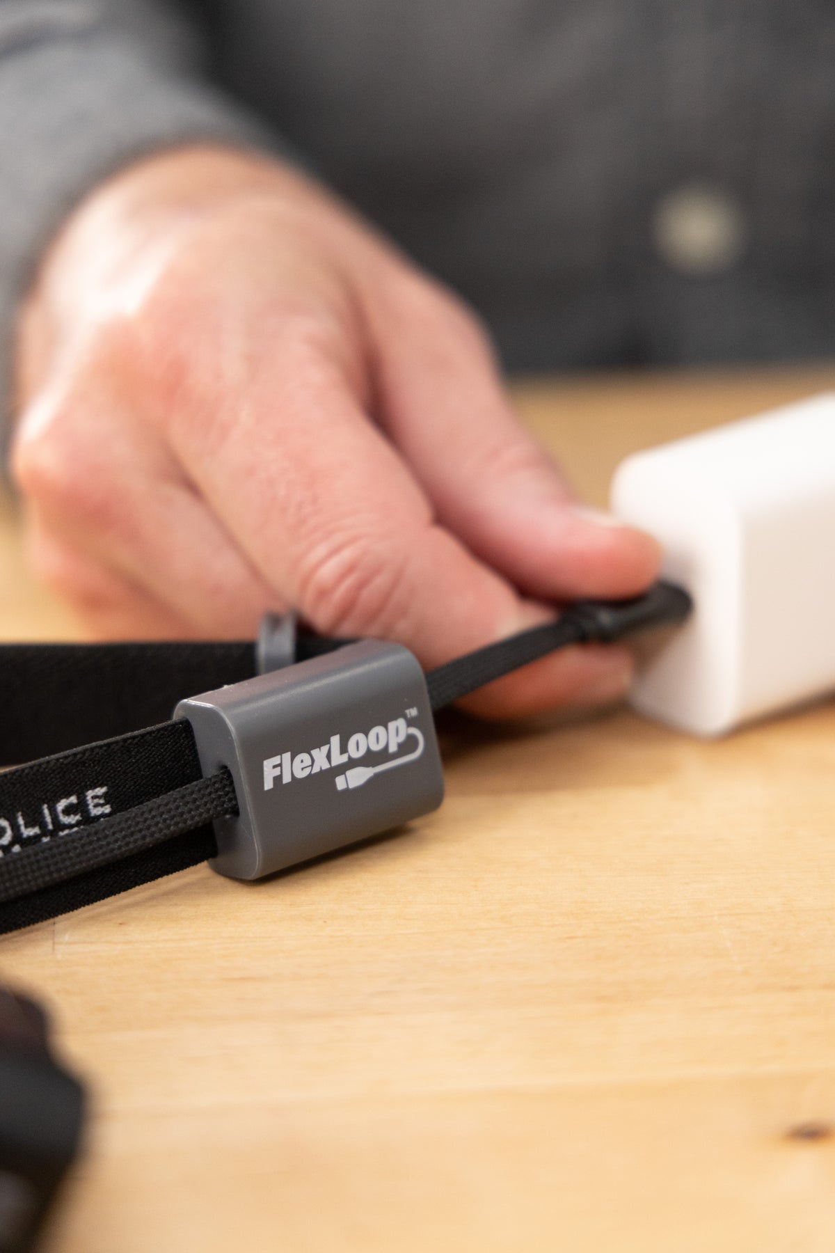 Person plugging in a FlexLoop headlamp on a wooden surface