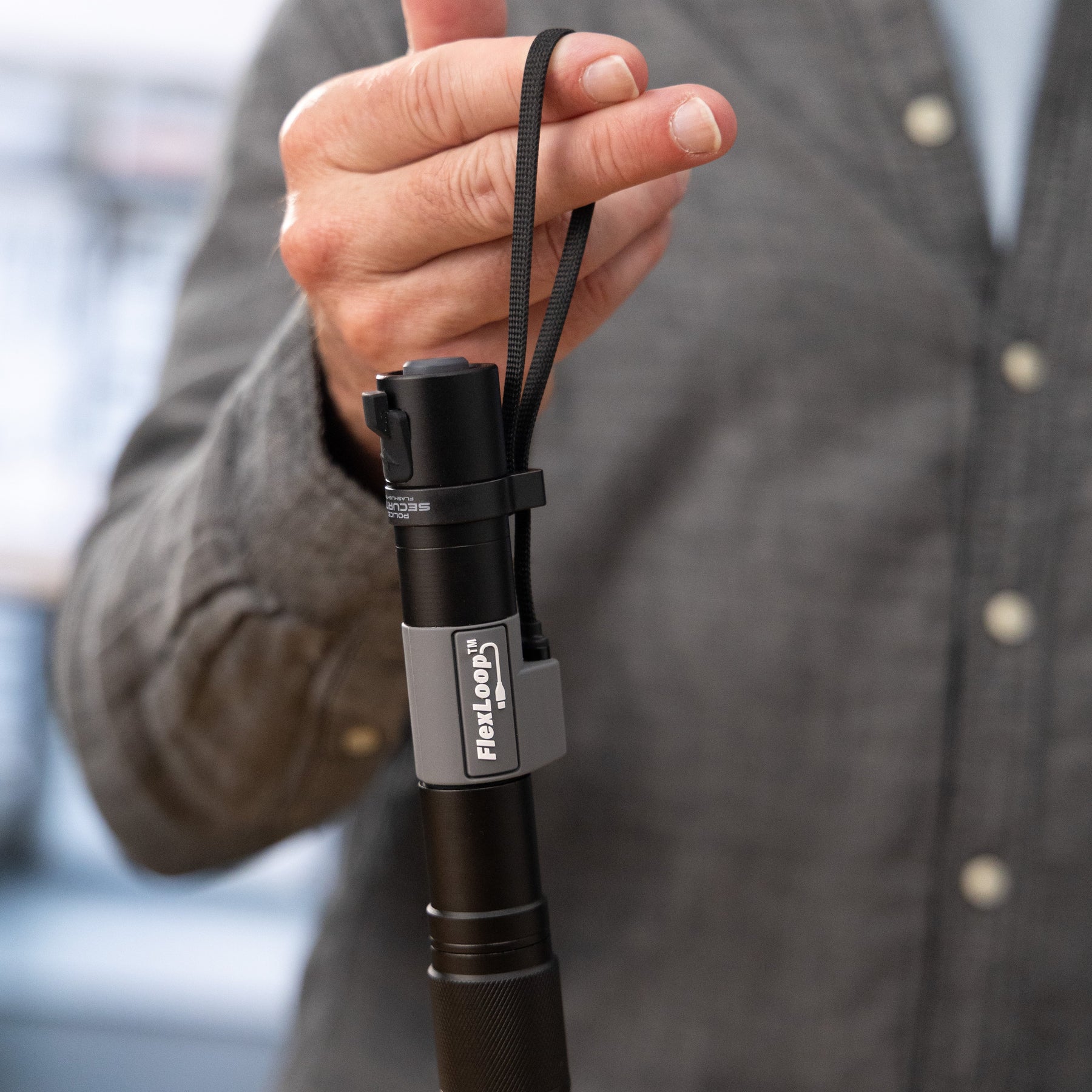 Person holding a Flexloop Aura RX flashlight over a wooden surface