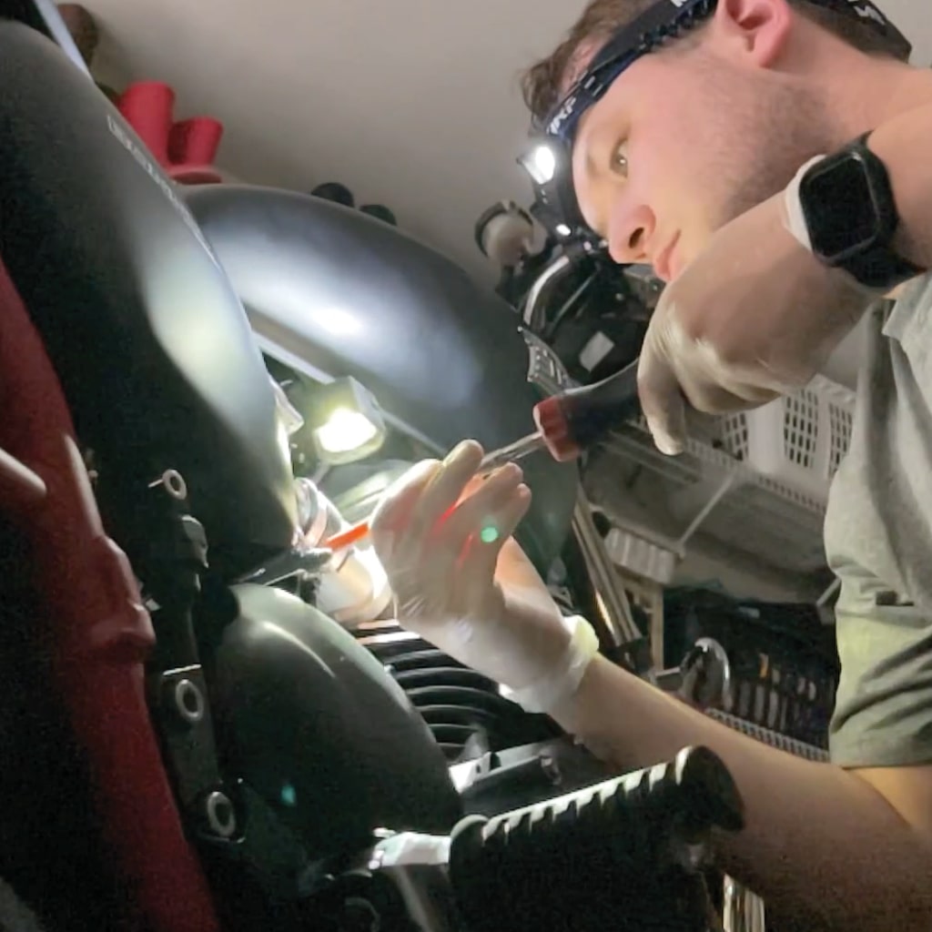 an image of a man fixing a motorcycle hands free thanks to his headlamp he's wearing